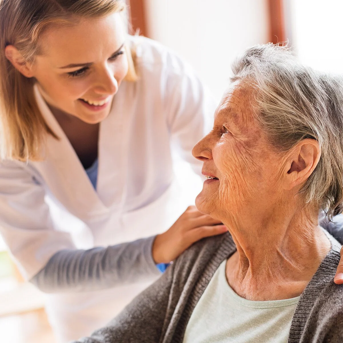 Health visitor and a senior woman during home visit. Health visitor and a senior woman during home visit. A nurse talking to an elderly woman.